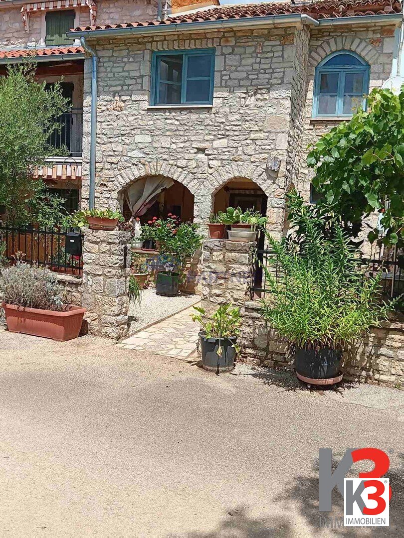 Steinhaus in der Mitte einer Reihe mit freiem Blick auf die grünen Felder